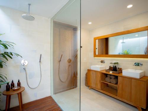 een badkamer met een douche, een wastafel en een spiegel bij Cocana Resort Gili Trawangan in Gili Trawangan