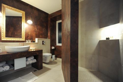 a bathroom with a sink and a toilet and a mirror at Silver & Gold Luxury Rooms in Zadar
