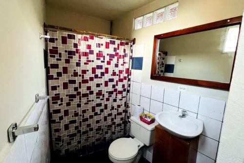 a bathroom with a toilet and a sink and a mirror at Cómoda habitación privada 2 personas FULL BED & FULL SOFA CAMA in Puerto Ayora