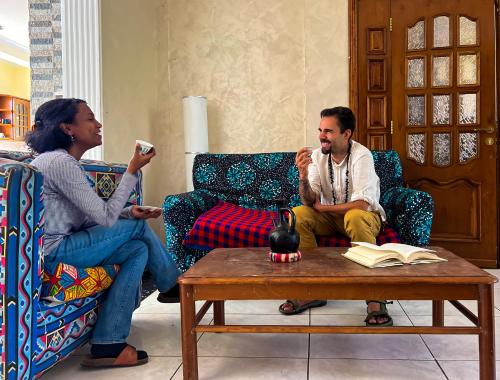 two people sitting in a living room playing a video game at Mad Vervet Backpackers Hostel in Addis Ababa