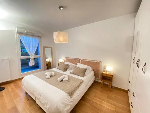 une chambre avec un grand lit avec deux serviettes dessus dans l'établissement Maïs Cottage, terrasse ensoleillée avec vue !, à Annecy