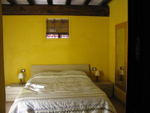 a yellow bedroom with a bed and two windows at Chalet della Rota in Marone
