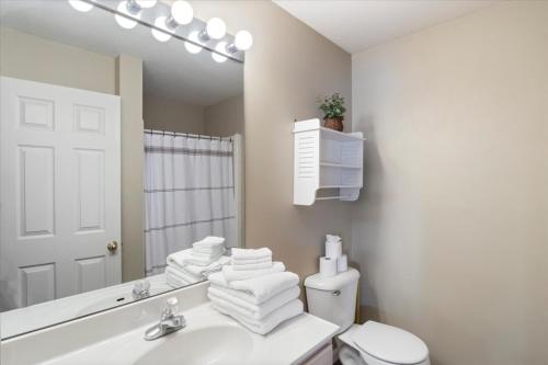 a bathroom with a sink and a toilet and a mirror at Condo at Parkview Bay - Your Lakefront Oasis in Osage Beach