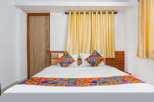 um quarto com uma cama branca e almofadas coloridas em FabHotel Lake View em Pune