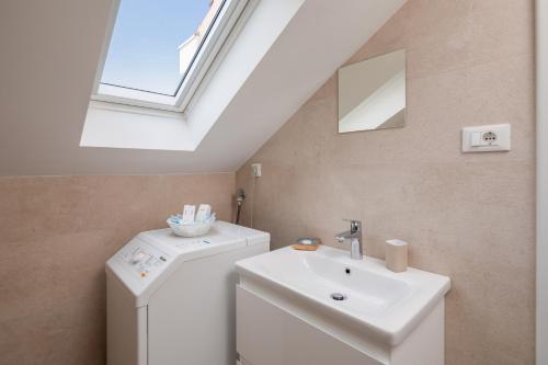 a bathroom with a sink and a washing machine at Epetium Beach Villa in Split