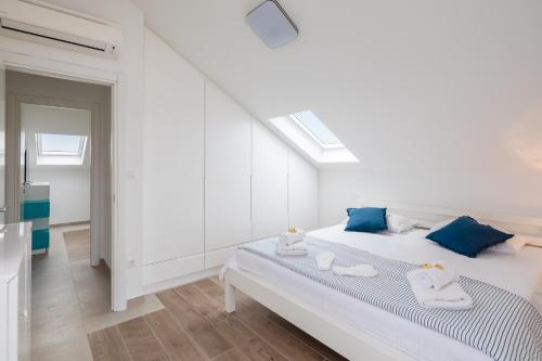 a white bedroom with a bed with blue pillows at Epetium Beach Villa in Split