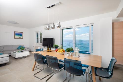 a dining room and living room with a table and chairs at Epetium Beach Villa in Split