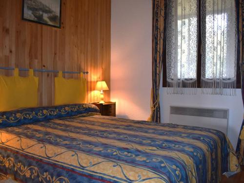 - une chambre dotée d'un lit avec une couverture bleue et jaune dans l'établissement À 2 min des pistes, appart 2 pièces cabine avec loggia vitrée et cuisine équipée - FR-1-580-36, à Font-Romeu-Odeillo-Via