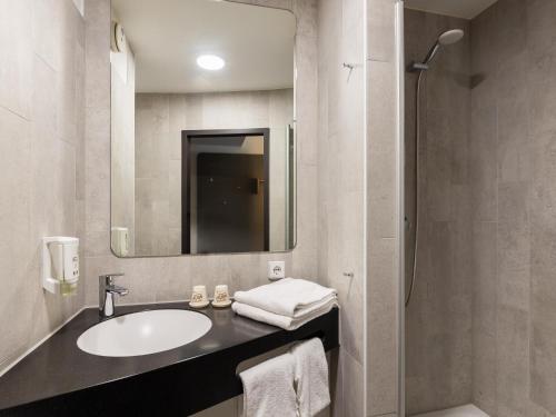 een badkamer met een wastafel, een spiegel en een douche bij B&B Hotel Düsseldorf City-Süd in Düsseldorf