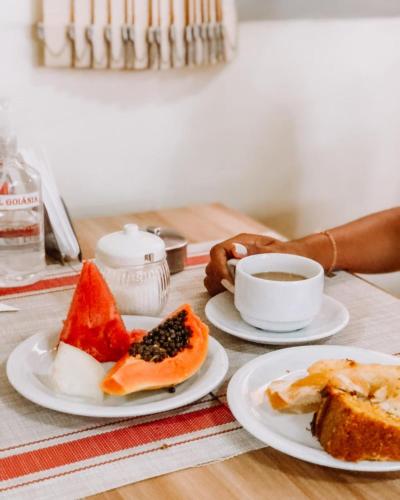 a table with two plates of food and a cup of coffee at Hotel Goiânia in Tucuruí