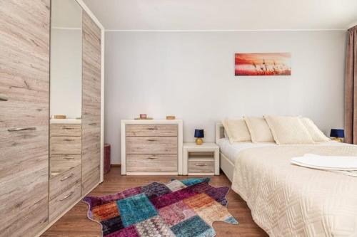 a white bedroom with a bed and a rug at Pušyno Apartment 1 in Klaipėda
