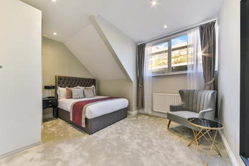 a bedroom with a bed and a chair and a window at Avari Apartments - Hatton Collection in London
