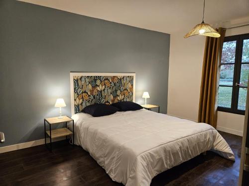 1 dormitorio con 1 cama grande y 2 mesas con lámparas en Le refuge de Loire, en Montrelais