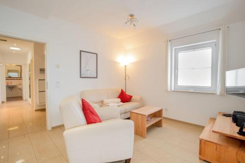 een woonkamer met een witte bank en rode kussens bij Kurparkresidenz Baabe Penthouse Windjammer in Baabe