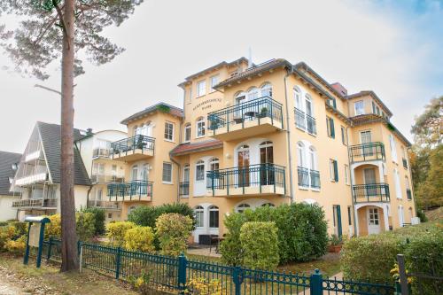 een groot geel gebouw met balkons en een hek bij Kurparkresidenz Baabe Penthouse Windjammer in Baabe