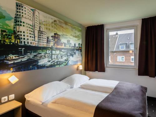 a hotel room with a bed and a painting on the wall at B&B Hotel Düsseldorf City-Süd in Düsseldorf