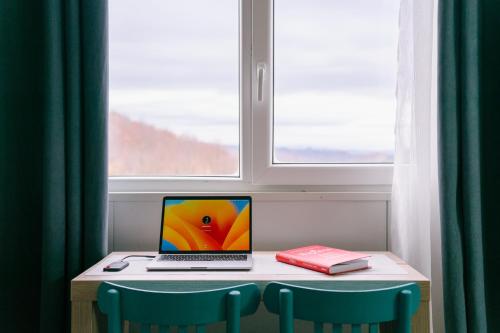 een laptop op een tafel naast een raam bij Greta Hillside 