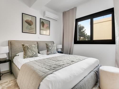 a white bedroom with a large bed and a window at Sanders Cruise-Spacious 2-bdr apt w2 balconies in Limassol