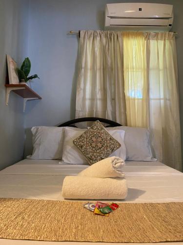Una cama con una manta blanca y almohadas. en Angel's Place Transient House en Tagbilaran City
