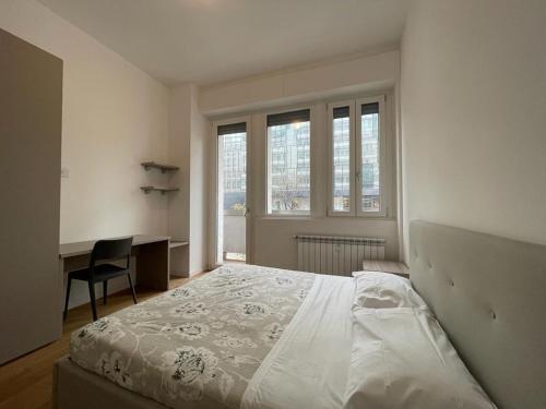 a bedroom with a bed and a desk and windows at IMHOME - Porta Vittoria in Milan