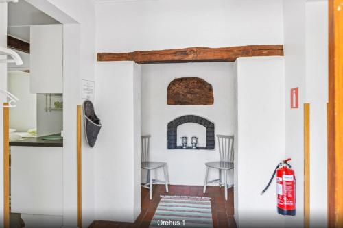 a kitchen with white walls and a fire extinguisher at Orehus - Country side cottage with garden in Sjöbo
