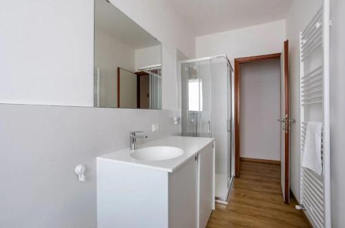 a white bathroom with a sink and a mirror at WoodenKey Asiago moderno bicamere in centro in Asiago