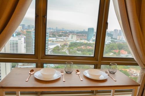 a table with plates and forks and spoons and a window at KL Art Nouveau Suite, MRT, Free Parking, Self Check In in Petaling Jaya