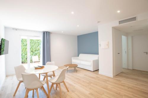 een woonkamer met een tafel, stoelen en een bank bij LOGIS LES CEPAGES / RESTAURANT LE RAISIN in Pont-de-Vaux