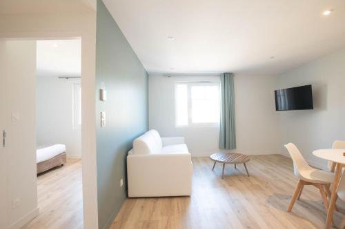 een woonkamer met een witte bank en een tafel bij LOGIS LES CEPAGES / RESTAURANT LE RAISIN in Pont-de-Vaux