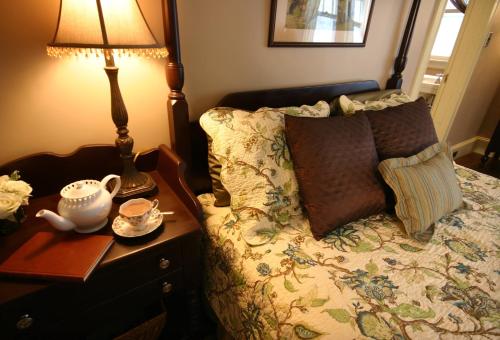 a bedroom with a bed and a table with a lamp at The Brewster Inn in Dexter