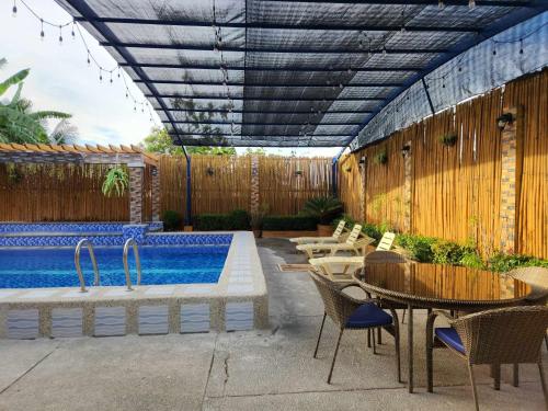 eine Terrasse mit einem Pool, einem Tisch und Stühlen in der Unterkunft TRD Private Hotspring Resort in Pansol