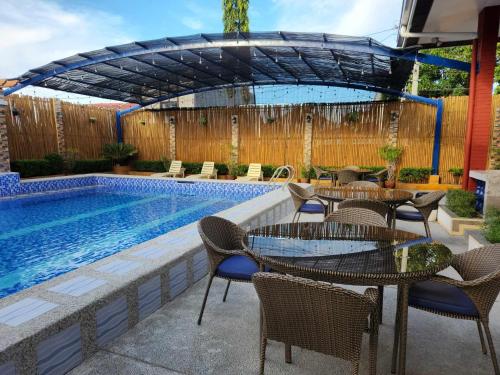 patio ze stołami i krzesłami obok basenu w obiekcie TRD Private Hotspring Resort w mieście Pansol
