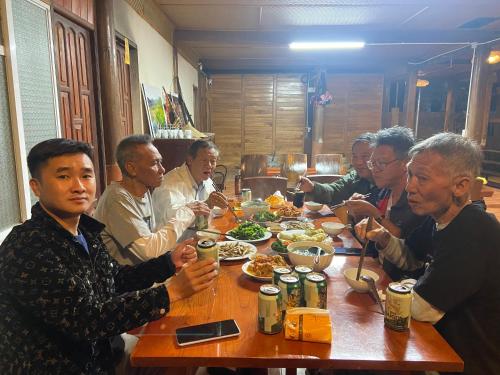un grupo de personas sentadas alrededor de una mesa comiendo comida en Ba Bể Hada Homestay, en Ba Be18