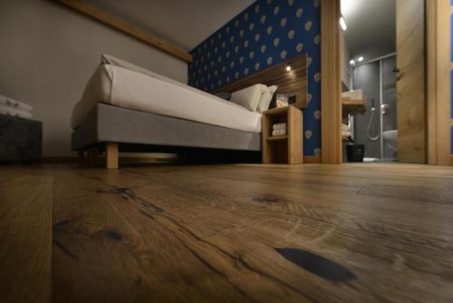 a bed in a room with a wooden floor at Hotel Galli's - Centro in Livigno