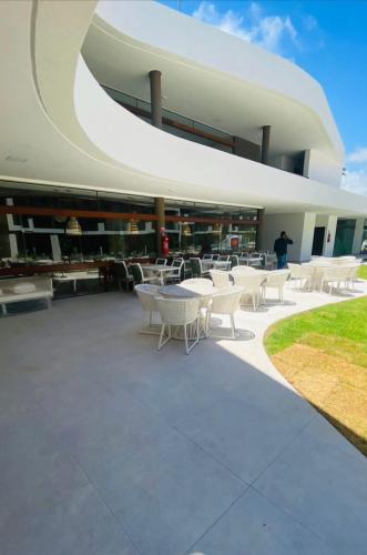 a building with white tables and chairs in front of it at Makia Flat Muro Alto in Porto De Galinhas