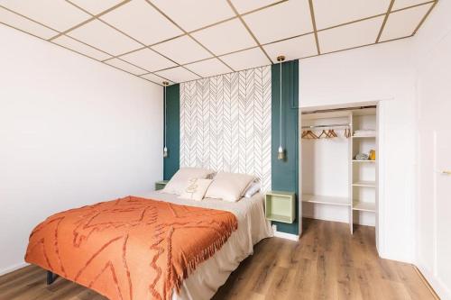 une chambre avec un lit avec une couverture orange dans l'établissement Appartement cozy en face de la gare - Saint-Brieuc, à Saint-Brieuc
