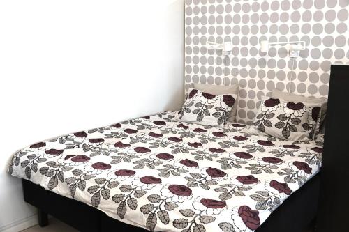 1 cama con edredón de flores y almohadas en un dormitorio en Charming city studio en Tampere