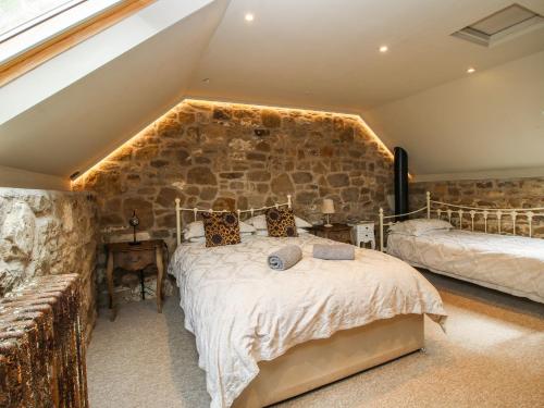 a bedroom with a stone wall and a bed at Corn House in Plaish