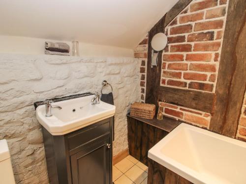 a bathroom with a sink and a brick wall at Corn House in Plaish