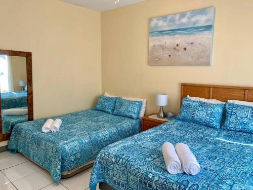 Cette chambre comprend 2 lits et un miroir. dans l'établissement SUITE 3, Blue Pavilion - Beach, Airport Taxi, Concierge, Island Retro Chic, à West Bay