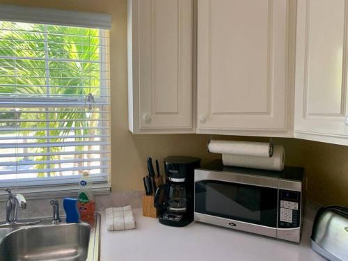 a kitchen counter with a microwave and a sink at SUITE 2B, Blue Pavilion - Private Executive Bedroom in Shared Suite - Beach, Airport Taxi, Concierge, Island Retro Chic in West Bay