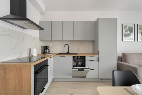 una cocina con armarios blancos y fregadero en Tasteful Beige Apartment with Parking by Renters en Poznan