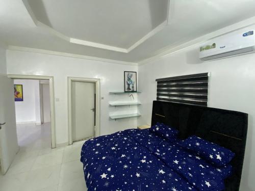 Schlafzimmer mit einem Bett mit blauer Decke in der Unterkunft MilesVilla Apartments in Enugu