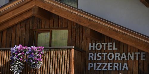 a wooden building with a balcony with flowers on it at Hotel Galli's - Centro in Livigno