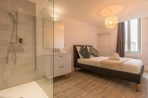 une chambre avec un lit et une douche en verre dans l'établissement ATYPIQUE - 2 chambres avec salles de bains, cuisine équipée, parking gratuit, à Castelsarrasin