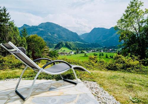 a chair sitting on top of a field with mountains at Ferienhaus sHäuserl in Landl