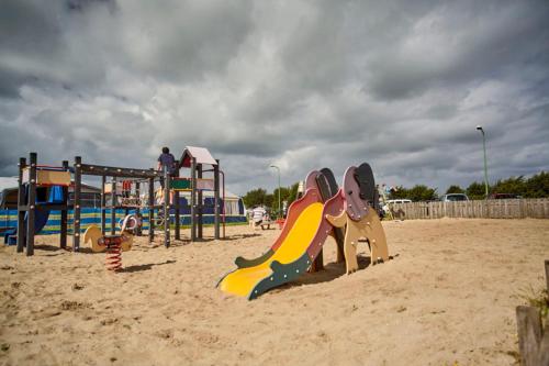 un parque infantil con un tobogán en la arena en Strandcamping Jagtveld, en s-Gravenzande