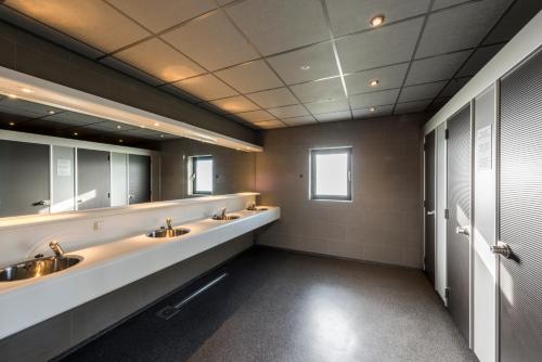a bathroom with two sinks and two mirrors at Strandcamping Jagtveld in 's-Gravenzande