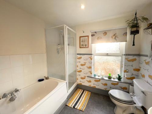 a bathroom with a tub and a toilet and a sink at Large Room with own TV and cereal and toast breakfast in Newhaven in Tarring Neville