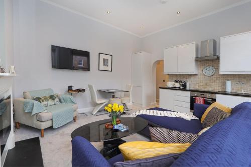 ein Wohnzimmer mit einem blauen Sofa und einem Tisch in der Unterkunft Cosy Kensington flat, 2 min to tube in London